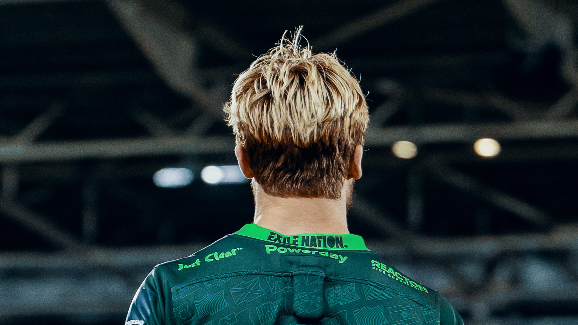 The back head and shoulders of a rugby player on the pitch wearing London Irish&rsquo;s team kit