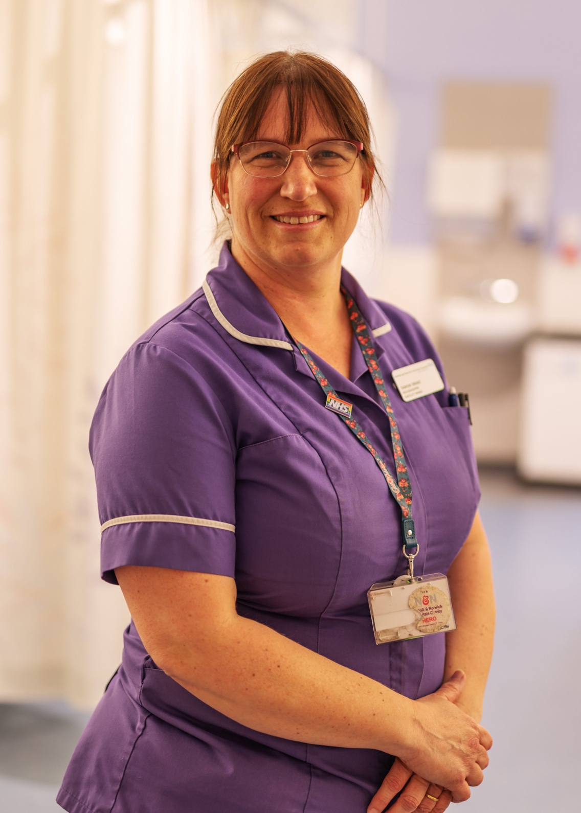 A smiling female nurse in purple scrubs