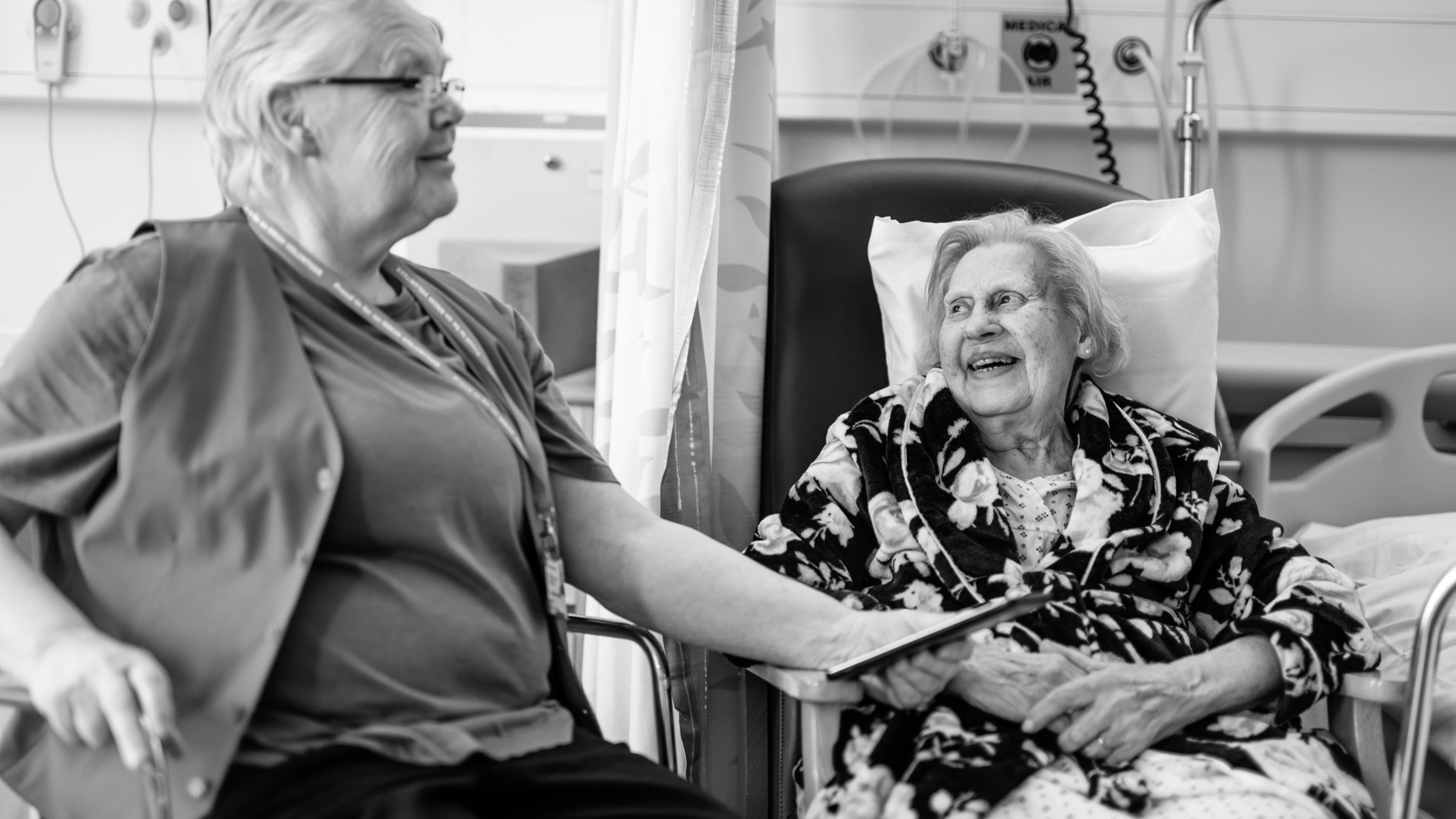 Helpforce female volunteer talking with an elderly female patient