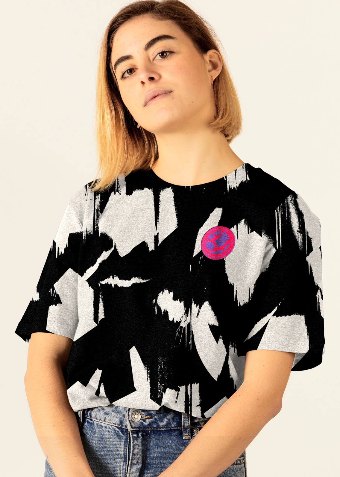 A confident woman wearing a branded Goal Power t-shirt tucked into her vintage jeans.